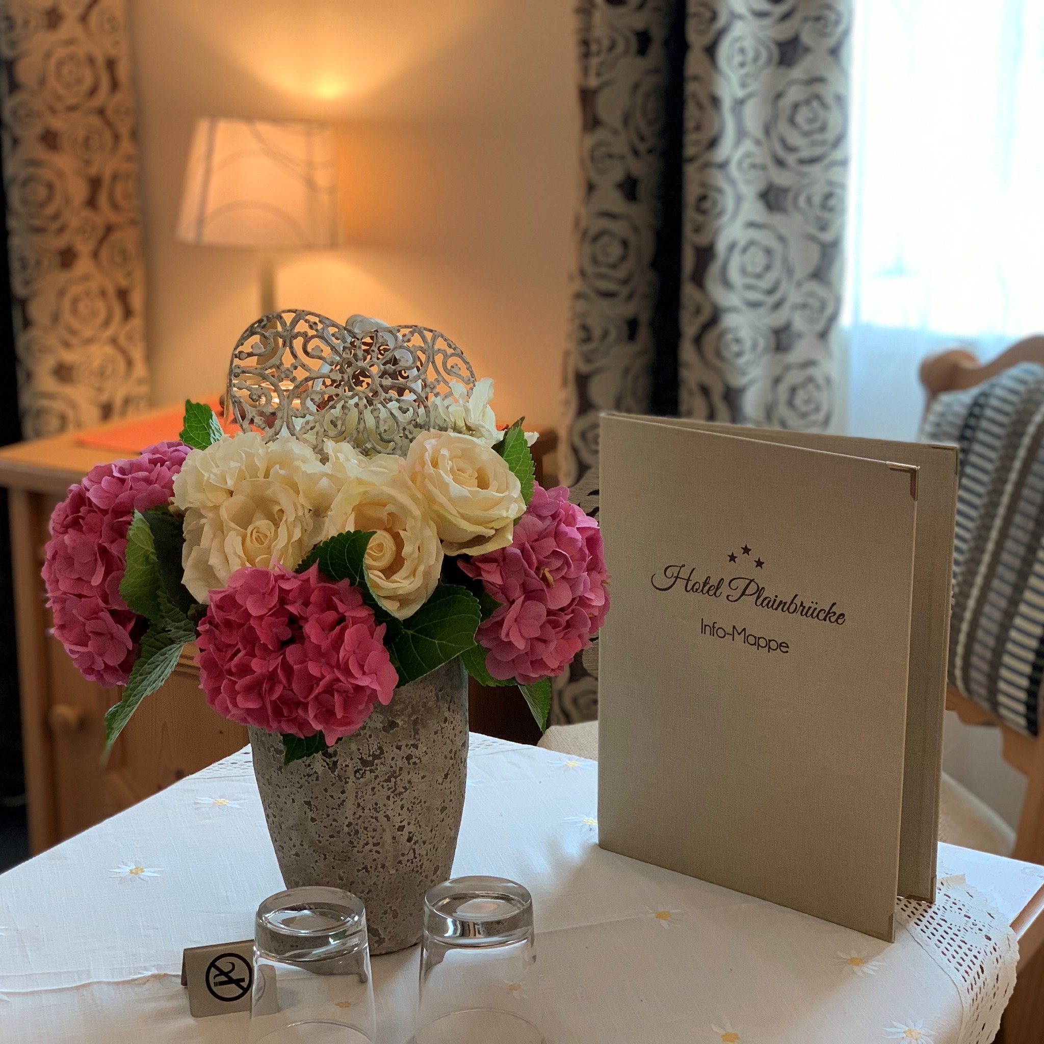 Blumenstrauß und Hotel-Infomappe auf einem Tisch im Hotel Plainbrücke